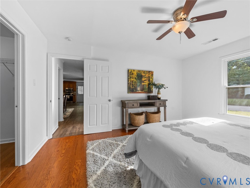 Hardwood flooring, ceiling fan with integrated light fixture, multi-pane window, and six-panel interior doors