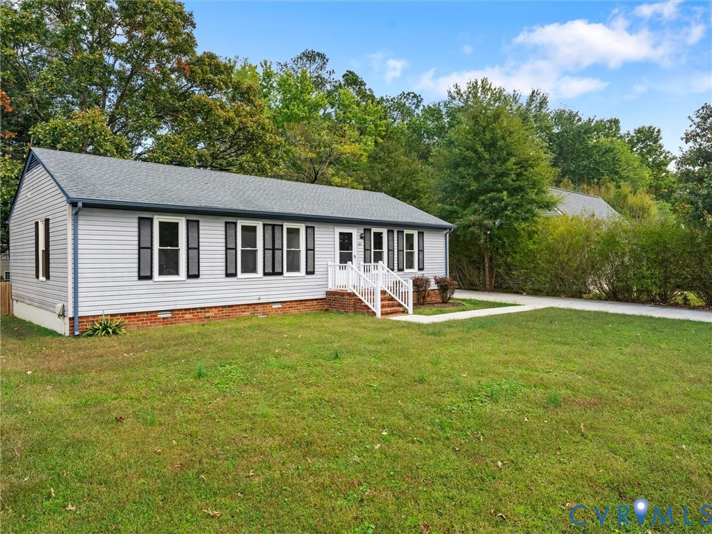 Single-story exterior featuring gray vinyl siding, a gabled roof, dark shutter accents, brick foundation trim, and a white railing entry Single-story exterior featuring gray vinyl siding, a gabled roof, dark shutter accents, brick foundation trim, and a white railing entry