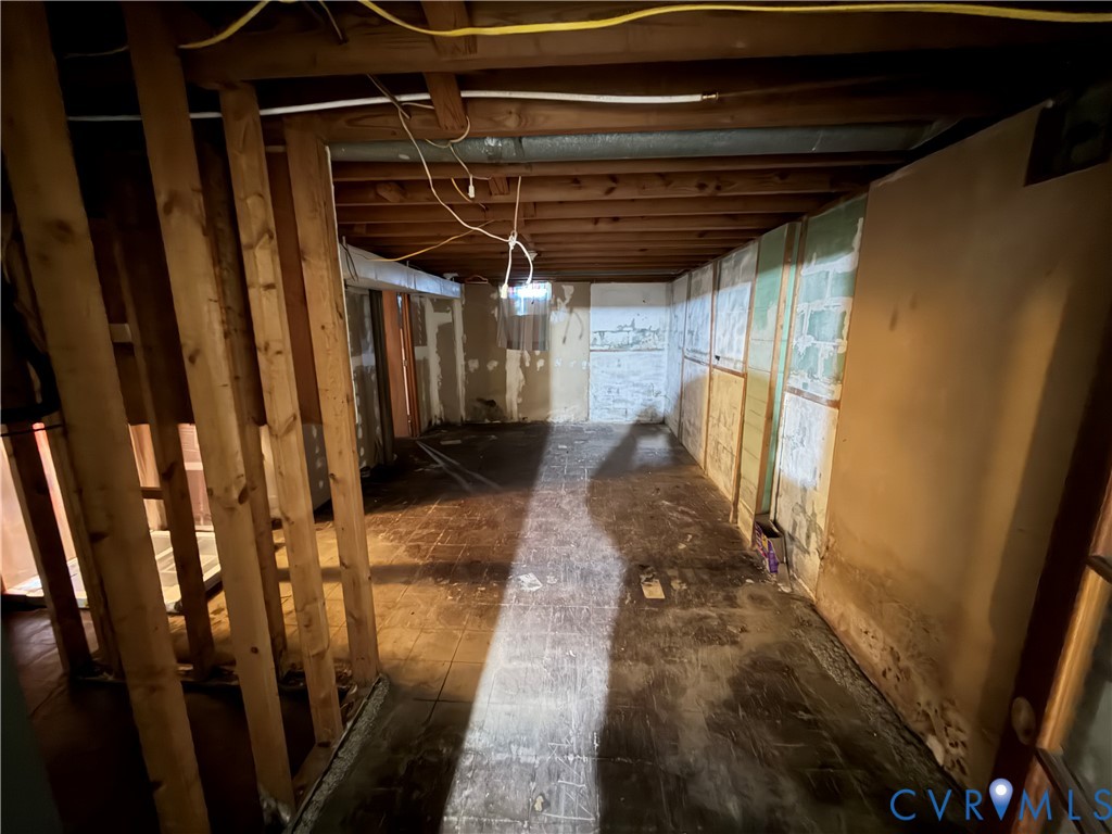 Unfinished lower level featuring exposed wood joist ceiling, concrete block wall construction, and exposed wood wall framing