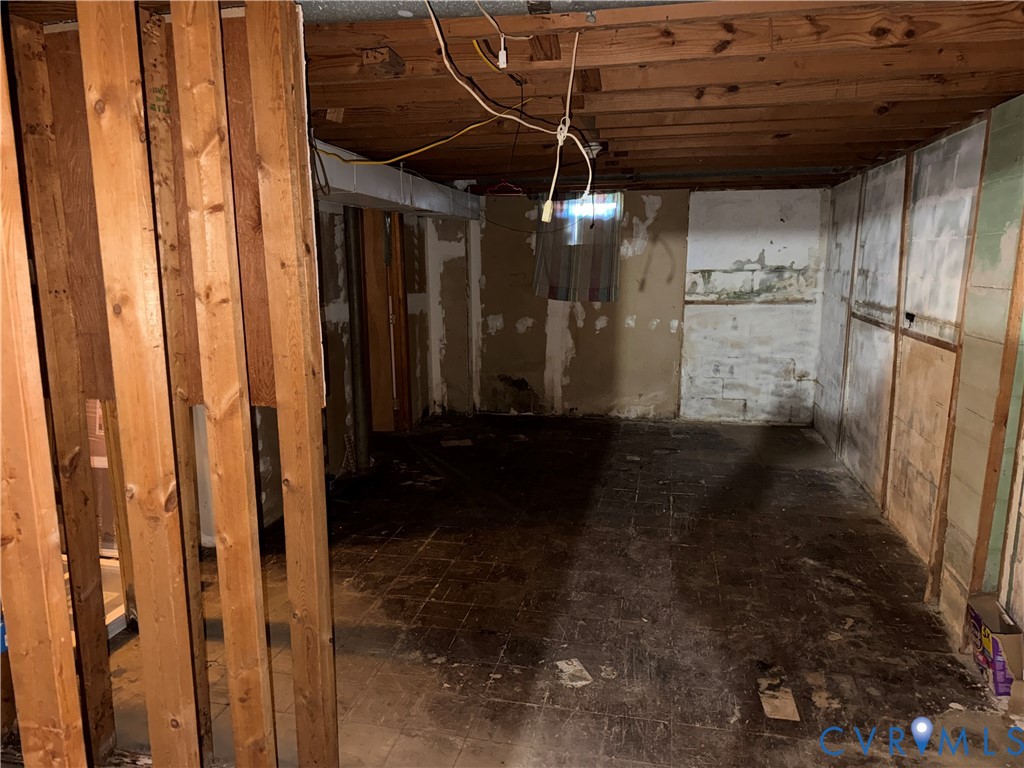 Unfinished lower level featuring exposed wood-stud framing, exposed ceiling joists, masonry walls, and a recessed window
