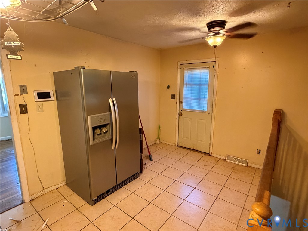 Stainless steel side-by-side refrigerator, ceramic tile flooring, and ceiling-mounted light fixture with integrated fan