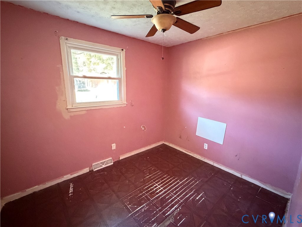 Room featuring dark square tile flooring, a single-hung window, and a ceiling-mounted fan with integrated lighting