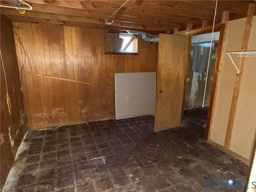 Interior space featuring wood paneling, tile flooring, a window, and a door