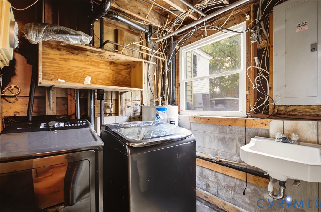 Utility area featuring a wall-mounted basin, single-hung window, exposed timber framing, and electrical service panel