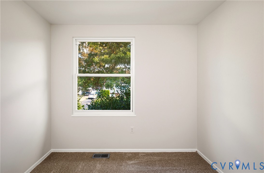 Neutral-toned interior walls featuring a double-hung window with exterior tree foliage