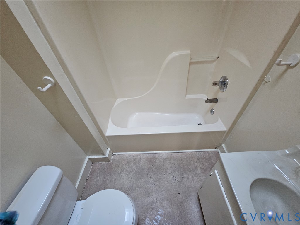 Full bathroom featuring a molded composite tub and shower surround, a standard-height toilet, and a vanity with an integrated basin Full bathroom featuring a molded composite tub and shower surround, a standard-height toilet, and a vanity with an integrated basin