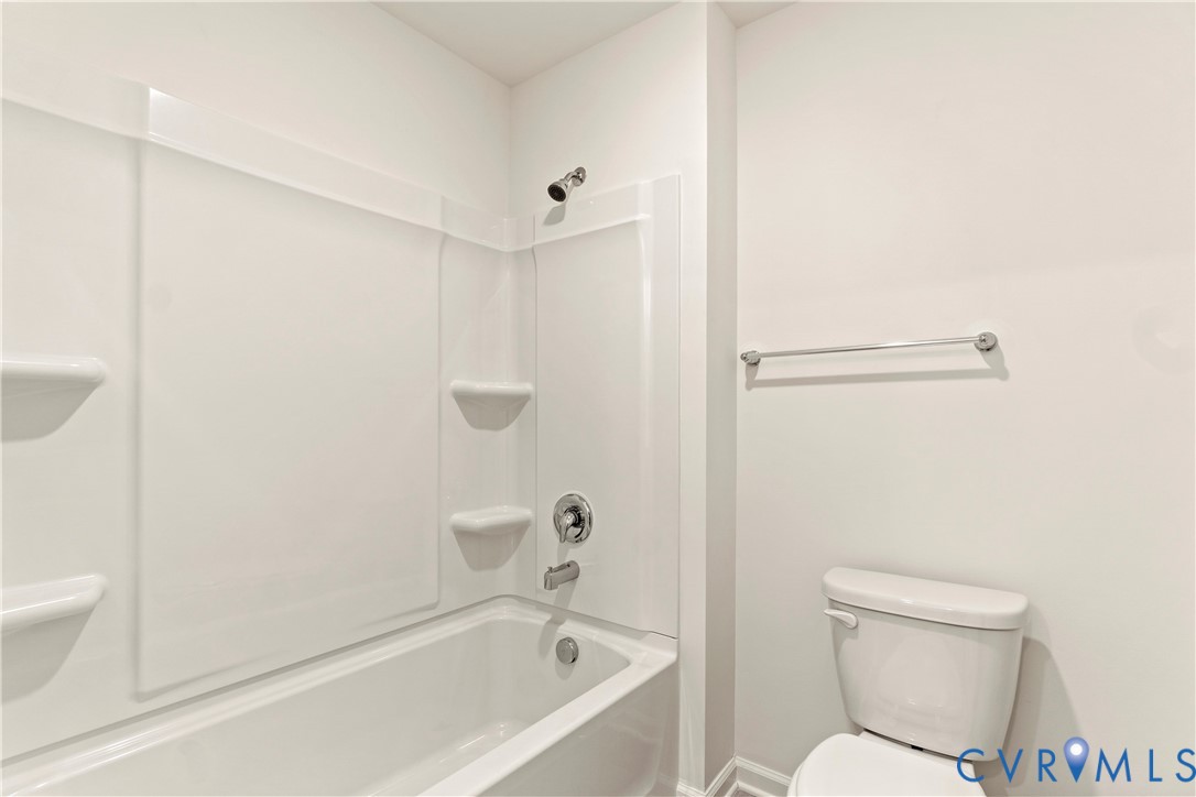 White tub and shower combination with integral shelving and chrome fixtures
