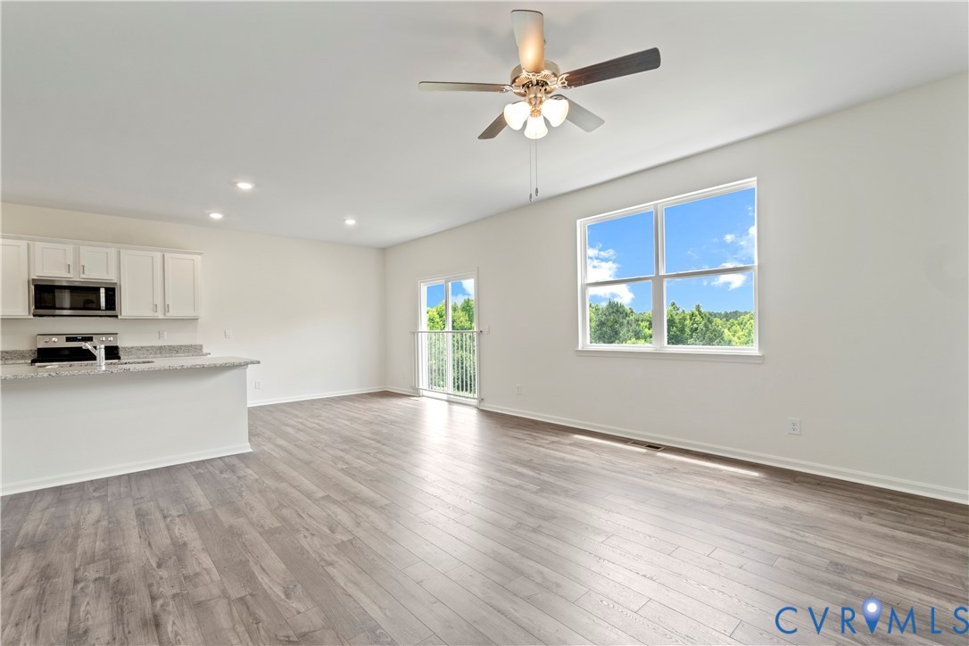 Open-concept living area featuring wood-finish flooring, recessed lighting, and a ceiling fan