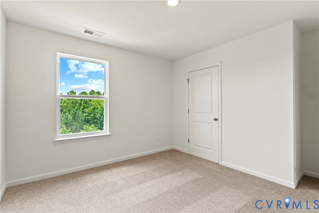 Light-filled interior space featuring a large window, neutral wall paint, and textured carpet flooring