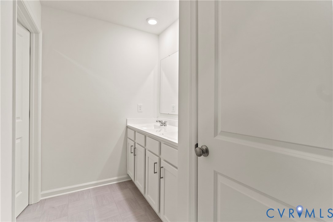 Bathroom vanity with dual sinks, a white countertop, and light gray cabinetry