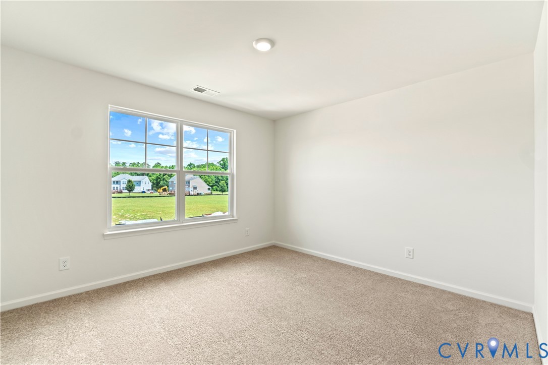 Bright interior space featuring a multi-pane window, neutral carpet, and white walls
