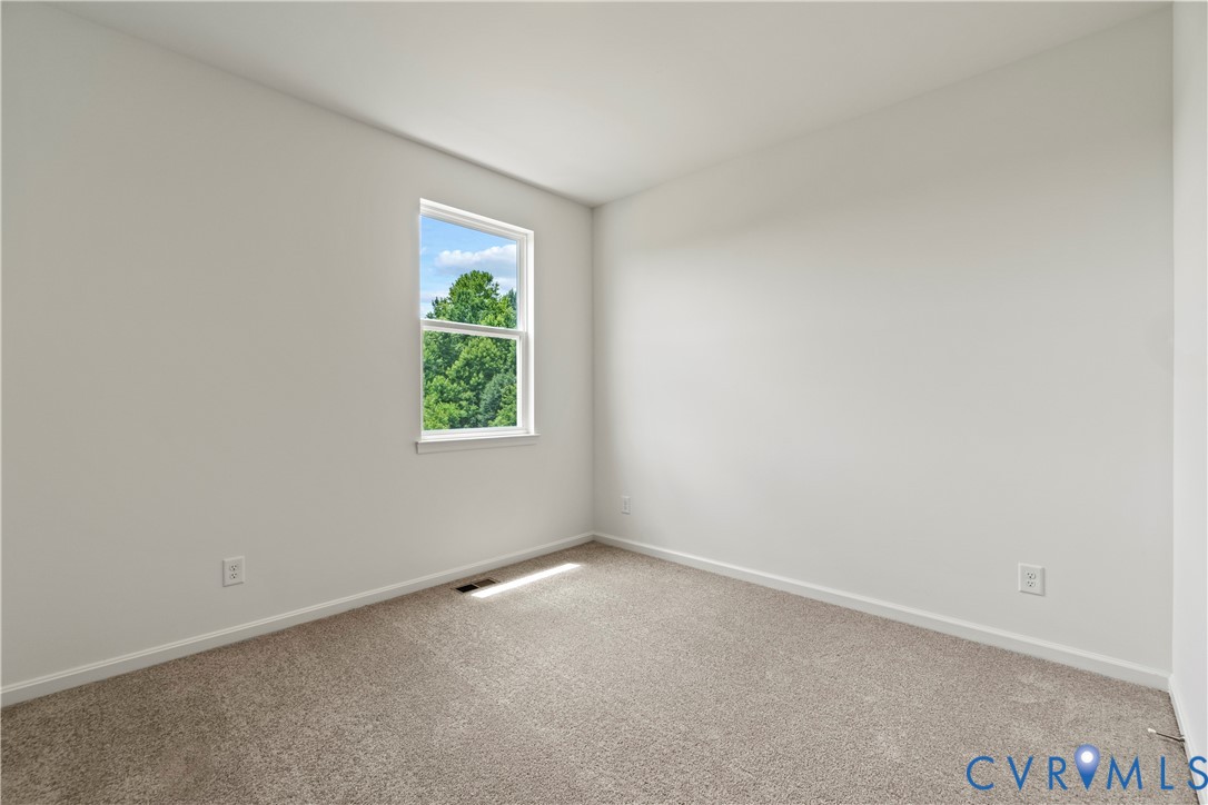 Bright interior room featuring a window with natural light, light neutral wall paint, and plush carpeting