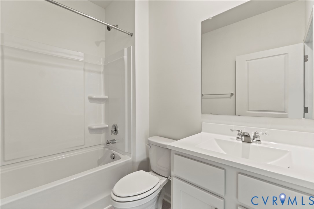 Bathroom featuring a shower/tub combination, single vanity with integrated sink, chrome fixtures, and a frameless mirror