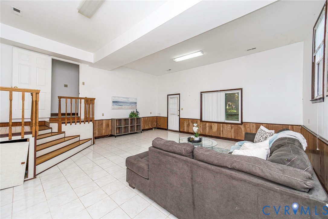 Tile flooring, wood-panel wall wainscoting, and a wooden staircase featuring a spindle railing
