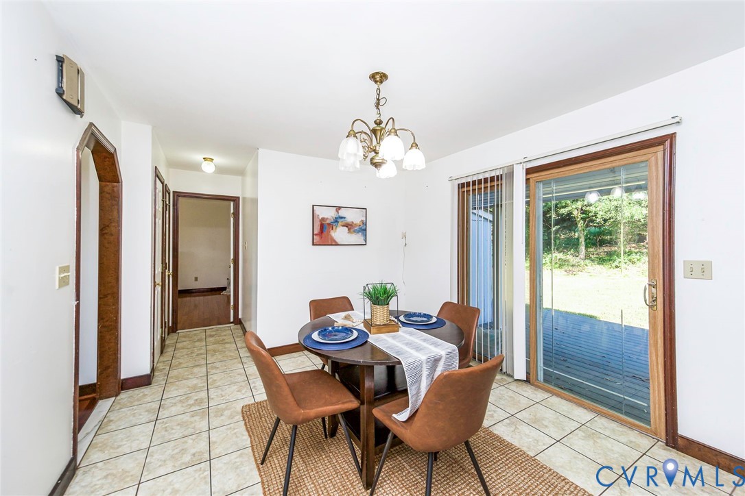 Dining area featuring light-toned ceramic tile flooring, a multi-arm chandelier, an arched doorway, and sliding glass doors with dark wood-finish trim