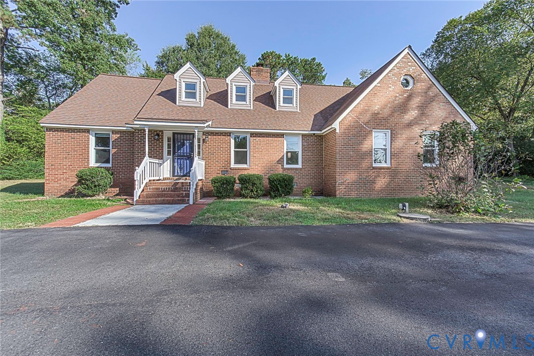 Traditional brick exterior featuring three front-facing dormer windows, a steep-pitched roof, circular gable window, and a paved brick walkway