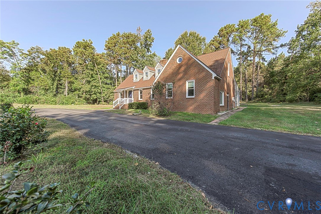 Brick exterior featuring a gabled roofline, dormer windows, a circular gable vent, and an asphalt driveway Brick exterior featuring a gabled roofline, dormer windows, a circular gable vent, and an asphalt driveway
