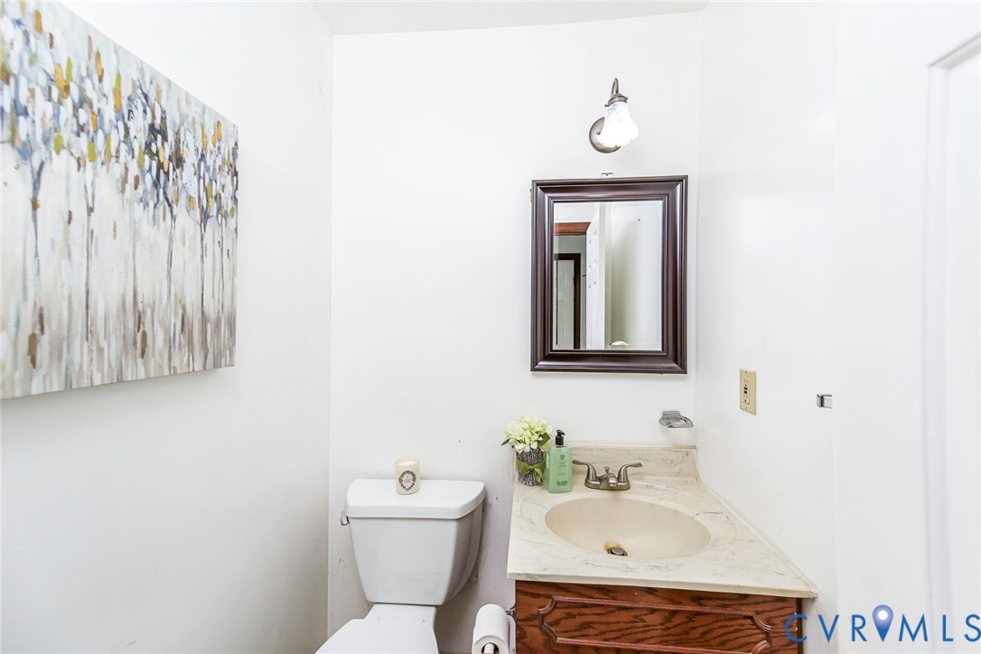Vanity with a neutral-toned countertop and integrated basin, dark-finish wood cabinetry, wall-mounted mirror, and overhead light fixture