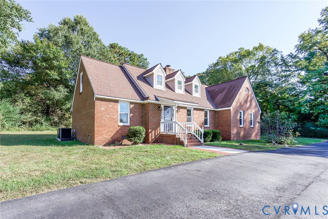 Traditional brick exterior featuring three front-facing dormer windows, a steep-pitched roofline, and an asphalt driveway Traditional brick exterior featuring three front-facing dormer windows, a steep-pitched roofline, and an asphalt driveway