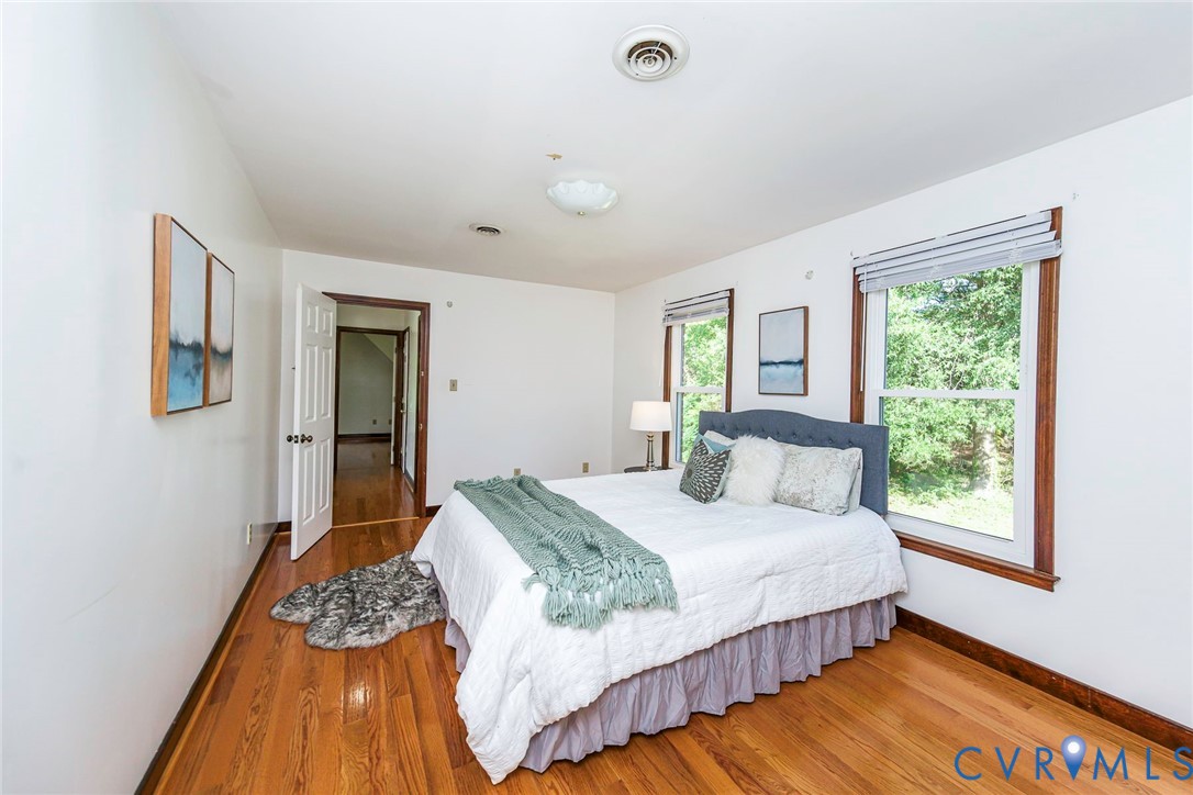 Bedroom featuring wood-finish flooring, two windows with wood casing, and ceiling-mounted lighting
