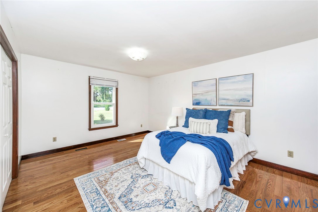 Spacious room featuring wood-finish flooring, neutral wall paint, and a double-pane window with wood trim