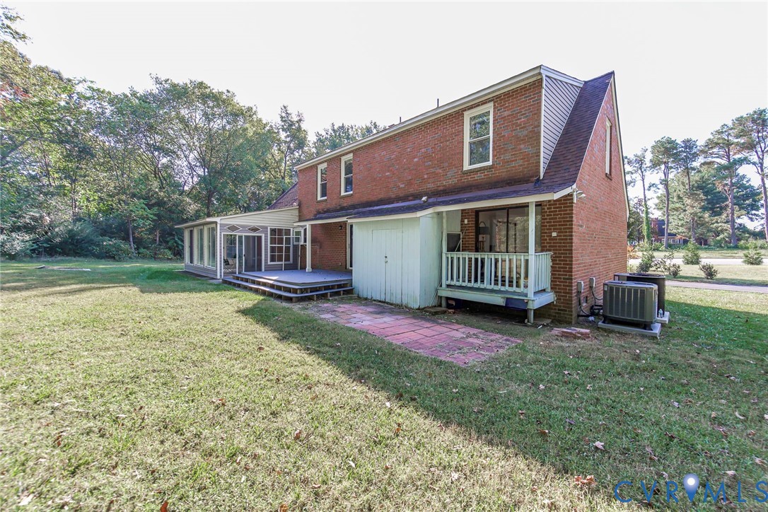 Brick exterior construction featuring a multi-level deck, enclosed sunroom, elevated rear porch, and stone-paved patio area Brick exterior construction featuring a multi-level deck, enclosed sunroom, elevated rear porch, and stone-paved patio area