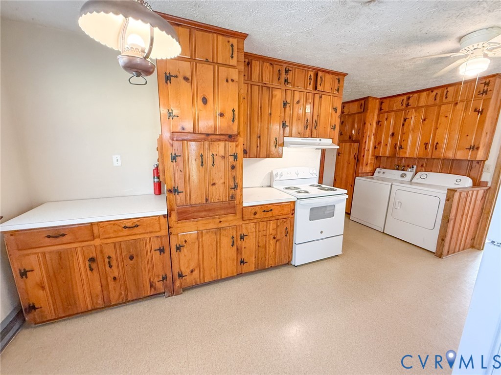 Custom knotty wood cabinetry featuring hardware with a dark finish, solid surface countertops, white freestanding range, and ceiling-mounted light fixtures