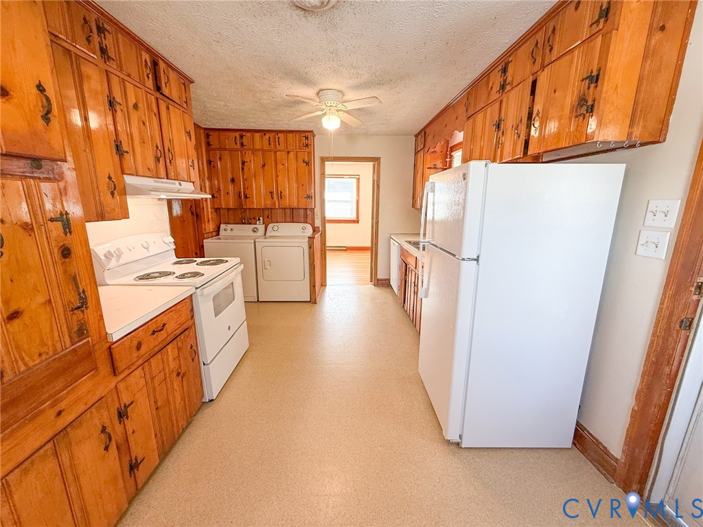 Kitchen featuring extensive wood-finish cabinetry, white built-in appliances, and a ceiling-mounted fan