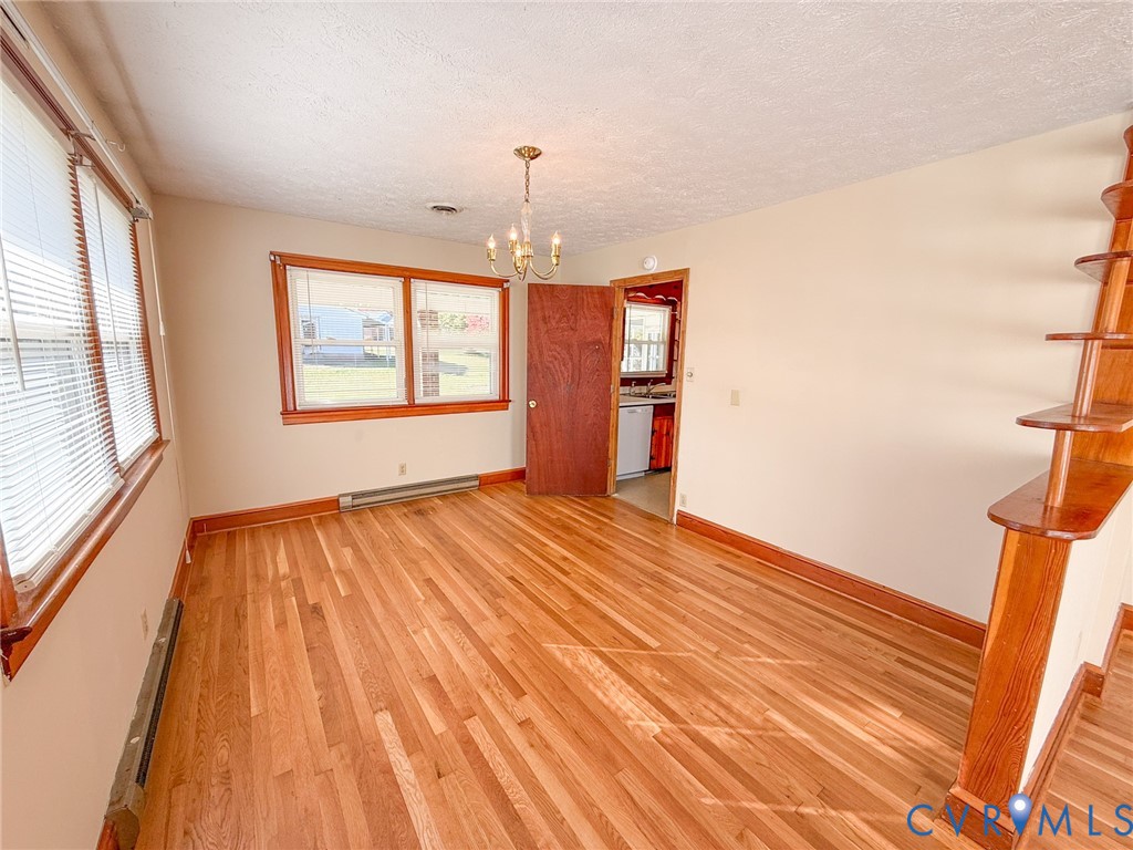 Hardwood flooring, multi-pane windows with wood trim, built-in wooden shelving, and a hanging chandelier