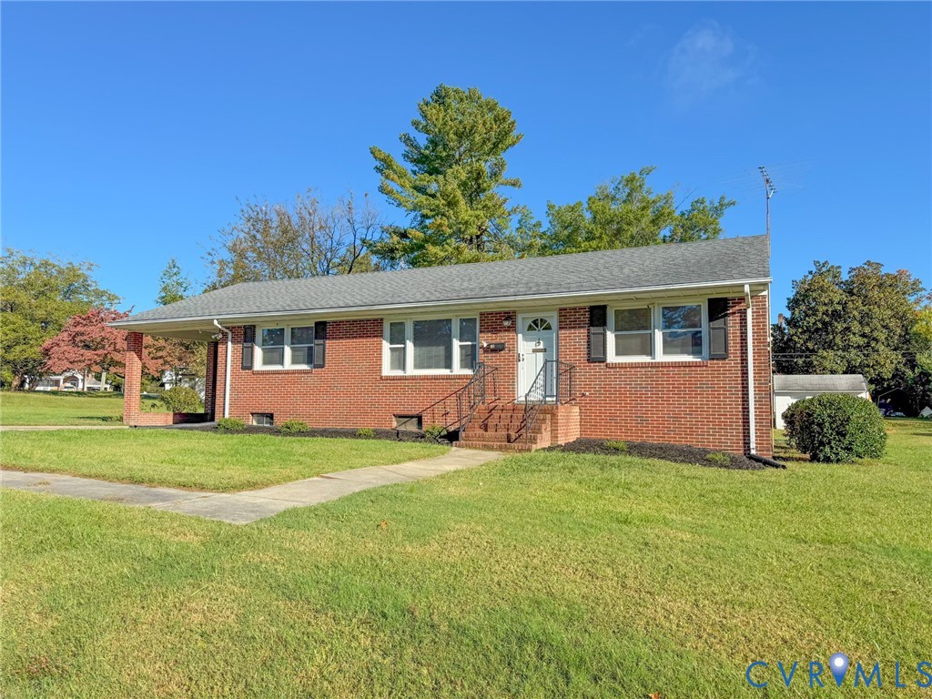 Single-story brick exterior featuring a covered side porch, asphalt shingle roof, black window shutters, and metal hand railings at the entry