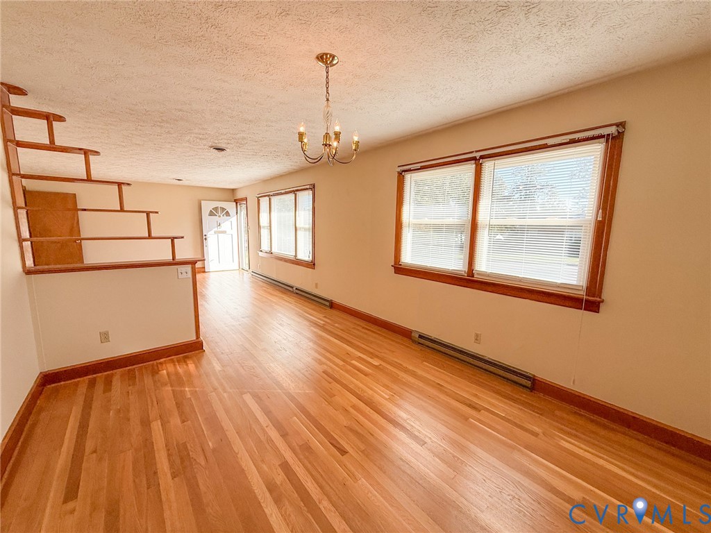 Interior space featuring wood-finish flooring, wood-trimmed windows, a multi-tiered open wood staircase railing, and a traditional multi-arm chandelier