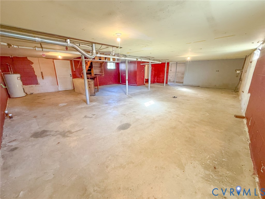 Unfinished basement featuring concrete flooring, masonry block walls, metal support columns, and an exposed water heater