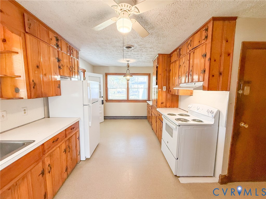 Kitchen featuring natural wood cabinetry, white countertops, built-in range, ceiling fan, and windowed exterior door