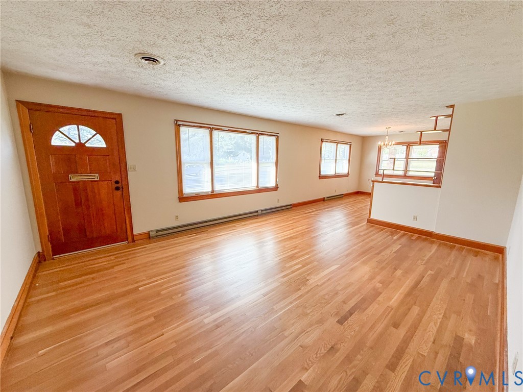 Interior space featuring wood-finish flooring, a wood-paneled front door with a decorative transom window, large picture windows, and a built-in room divider