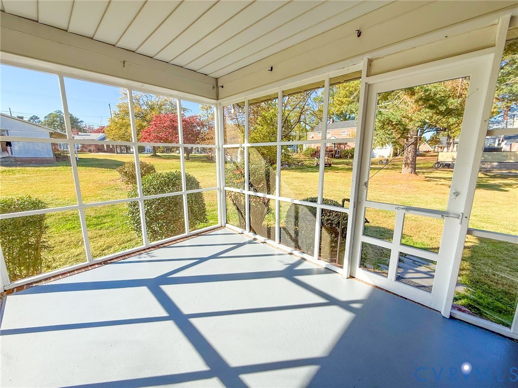 Enclosed porch featuring white framing, a screen enclosure, and solid surface flooring