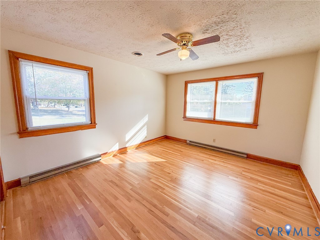 Interior space featuring wood-finish flooring, natural wood window trim, and a ceiling-mounted light fixture with a multi-blade fan