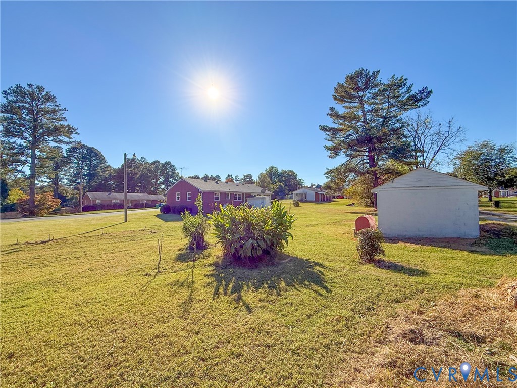 Expansive lot featuring a brick-exterior residence, a detached storage structure, and mature trees