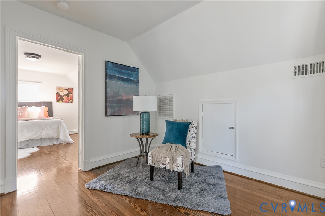 Sloped ceiling design featuring wood-finish flooring and a built-in wall access panel