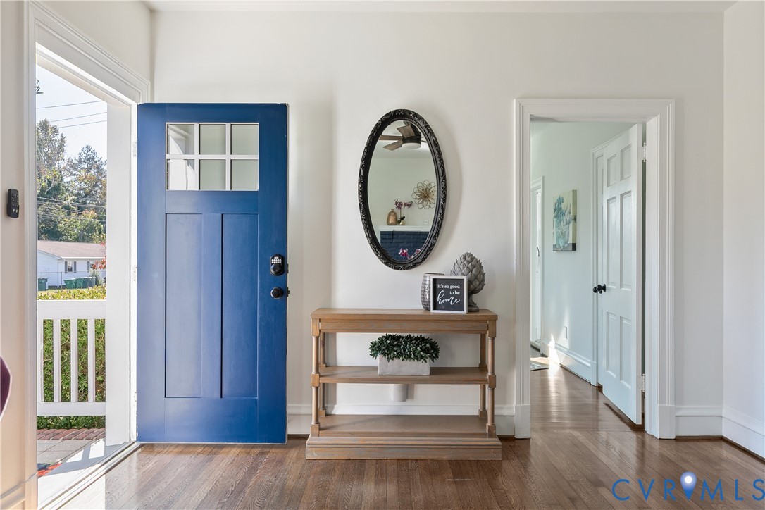 Entryway featuring a solid blue door with a six-pane glass transom, wood-finish flooring, and a multi-panel interior door