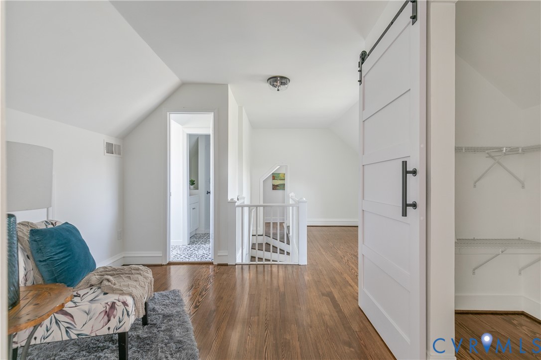 Interior space featuring wood-finish flooring, a white sliding barn door with matte black hardware, and an attached white railing system