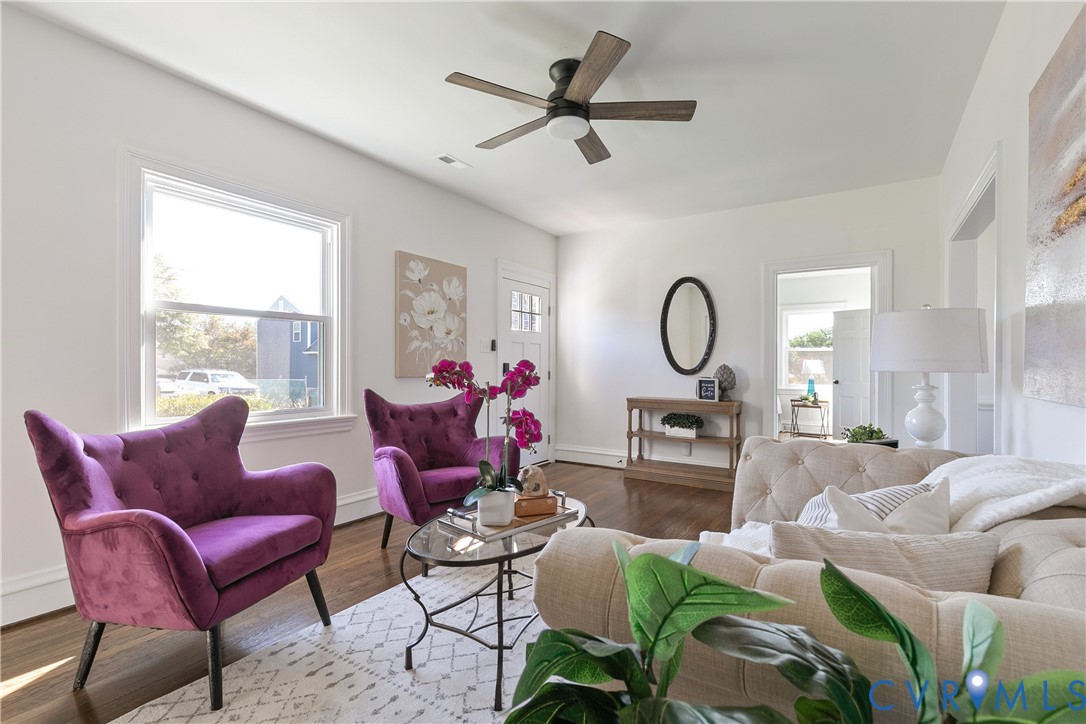 Living space featuring wood-finish flooring, large multi-pane window, and a central ceiling fan with integrated lighting