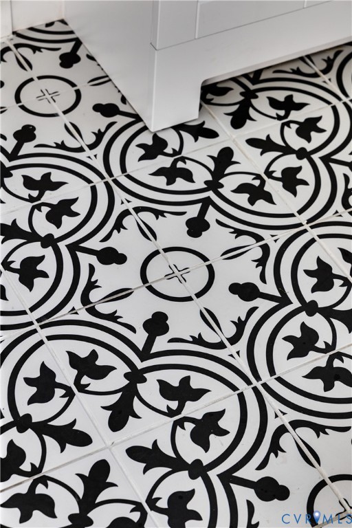 Decorative black and white patterned tile flooring featuring a high-contrast geometric floral motif and a solid white built-in cabinetry base