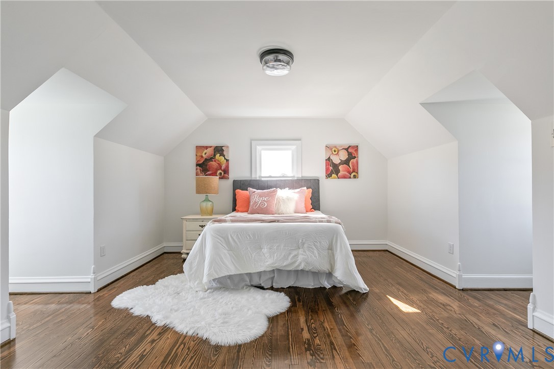 Vaulted ceilings with dormer-style architecture, wood-finish flooring, and a central ceiling-mounted light fixture