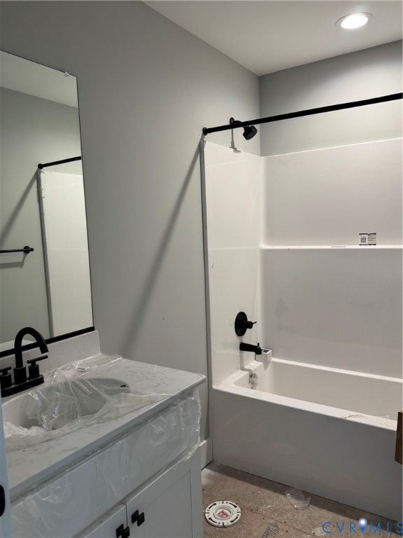 Bathroom featuring a vanity with a white composite countertop, undermount sink, matte black faucet, wall-mounted mirror, and a shower-tub combination with matte black fixtures