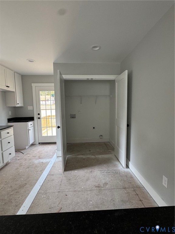 White cabinetry, dark countertops, recessed lighting, and a glass-paneled exterior door featuring a dedicated laundry closet with dual doors
