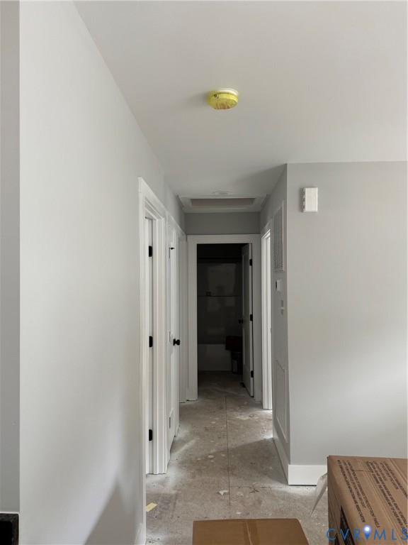 Neutral-toned interior hallway with white door casing, matte black hardware, and an integrated ceiling access panel