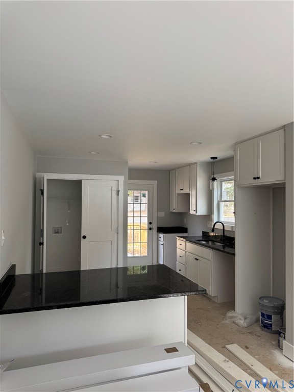 Kitchen featuring white shaker-style cabinetry, dark stone countertops, an integrated peninsula, recessed ceiling lighting, and a gooseneck faucet