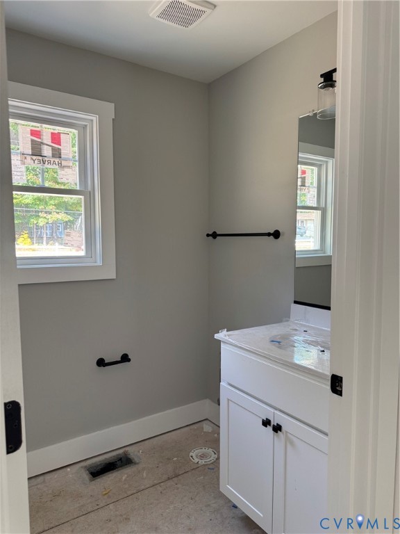 White vanity cabinet with a stone-top integrated sink, matte black hardware, vertical wall mirror, and matte black wall-mounted fixtures