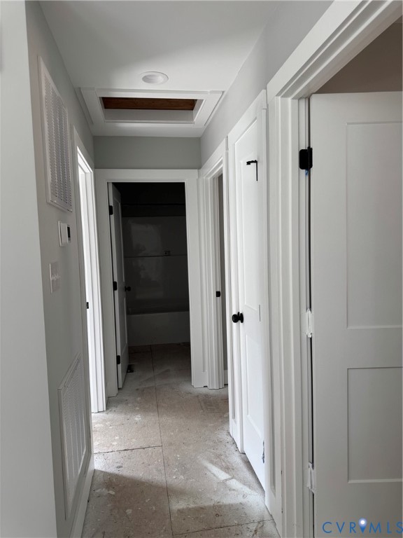 Hallway featuring two-panel interior doors with matte black hardware, recessed ceiling lighting, and neutral-toned tile flooring