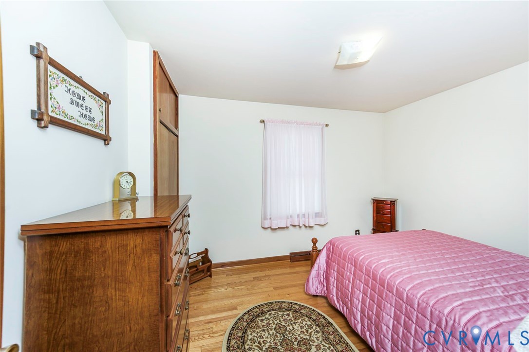 Room featuring wood-finish flooring, a built-in floor-to-ceiling storage closet, and a square-pane window with a curtain rod